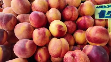 Parlak şeftaliler yaz güneşinde bir pazarda istiflenir..