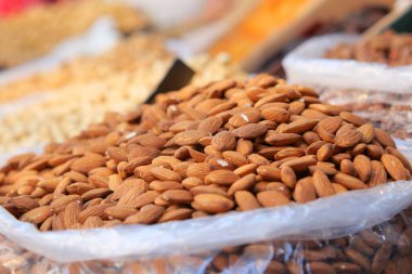 Bags of raw almonds sit at a market booth under natural light.
