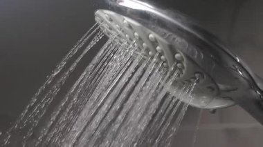 Parlak bir banyo ortamında şık bir duş başlığından su fışkırıyor..