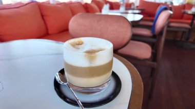 Taze demlenmiş kahve, sıcak bir kafe ortamında bir masada oturur..