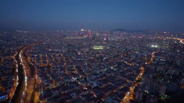 Parlak şehir ışıkları alacakaranlıkta sokakları ve binaları aydınlatıyor.