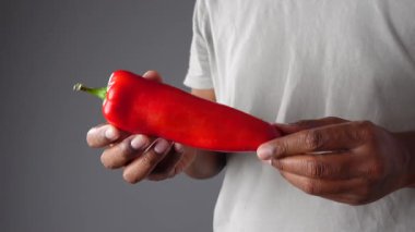 Adamın elinde lezzetli yemekler hazırlamaya hazır parlak kırmızı biber var..