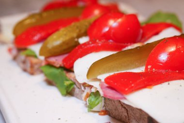 Domates, turşu ve marul katmanlı taze sandviç yemeye hazır..