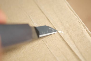 Karton kutuyu kesmek için bir alet bıçağı kullanılır..