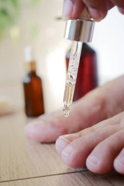 Bir insan cilt bakımı için ayağına yağ sürmek için damlatıcıyı kullanır..