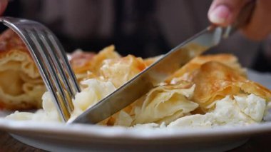 Sıcak bir yerde pul pul peynirli hamur işi kesmenin ve tadını çıkarmanın yakın görüntüsü.