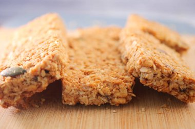 Tahta bir yüzeye oturmuş yulaf ve fındıklı gevrek granola barları.