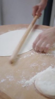 Eller ahşap bir yüzeyde düzgün bir hamur çemberi oluşturmak için çalışır..