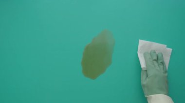 Birisi parlak bir yüzey üzerindeki lekeyi kağıt havluyla siliyor..