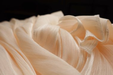 Narin beyaz kumaş nazik, dalgalı kıvrımlar ve katmanlar oluşturur..