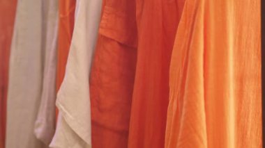 Canlı bir pazarda renkli turuncu ve beyaz kumaşlar sergileniyor..