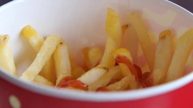 Taze pişmiş patates kızartması, bir kasede zengin ketçapla servis edilir..