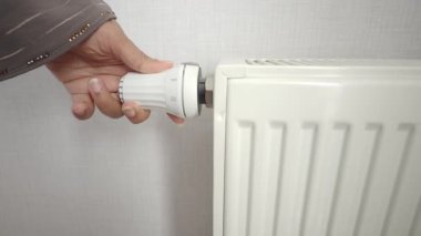 Bir el odadaki sıcaklığı kontrol etmek için radyatörün düğmesini çevirir..
