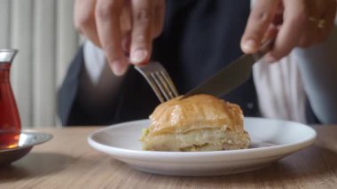 Bir kafede çayın keyfini çıkarırken bir parça baklava kesilir..