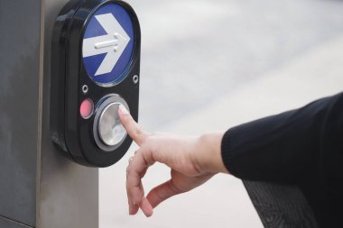 Meşgul bir kavşakta bir kişi yaya geçidi düğmesine basar.