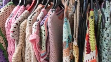 Parlak el yapımı tığ işi elbiseler ucuzluk mağazasında askılarda asılı..