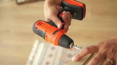 Biri elektrikli matkapla içeride ahşap bir raf kuruyor..