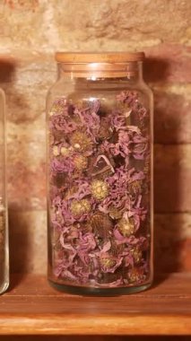 Renkli kurumuş çiçekler ahşap bir raftaki cam bir kavanozda sergilenir..