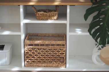 Örülmüş depolama sepetleri beyaz bir rafta durur ve güneş ışığı içeri akar..