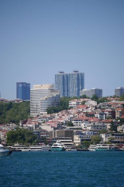 Gemiler açık bir günde canlı bir şehrin ufuk çizgisi yakınında suda yüzerler..