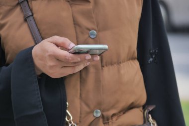 Sıradan bir açık hava ortamında duran kişi akıllı telefon kullanıyor..