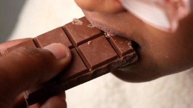 Bir çocuk abur cubur yerken büyük bir çikolata ısırığı alır..