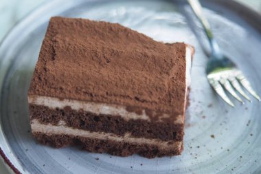 Zengin bir dilim çikolatalı pasta gümüş bir tabakta oturuyor, eğlenmeye hazır..