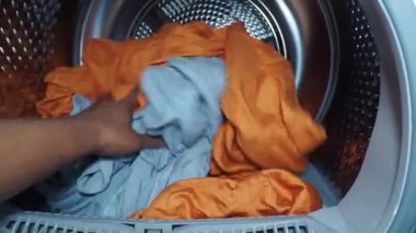Evde çamaşır yıkama günü için renkli giysileri çamaşır makinesine dolduruyorum..