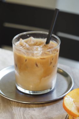 Ferahlatıcı bir buzlu kahve dilimlenmiş bir portakalın yanında metal bir tepside oturur..