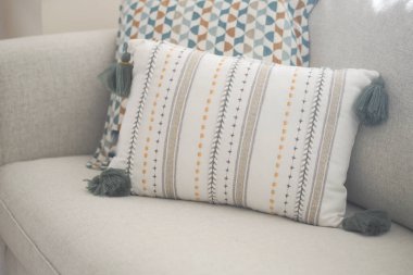 Şık püsküllü bir yastık, parlak bir odada, hafif bir kanepede yatıyor..