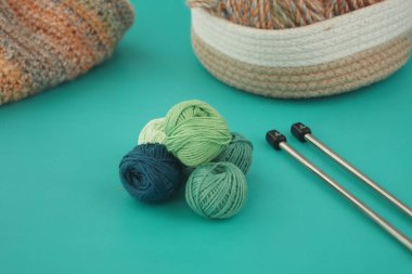 Renkli iplik topları ve örgü iğneleri parlak bir yüzeye yerleştirilmiştir..