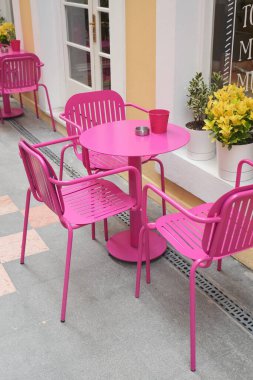 Parlak pembe sandalyeler ve masalar kafede neşeli bir ortam yaratır..