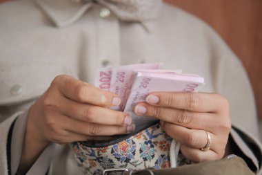 Bir insan sıcak bir odada elinde bir çanta varken banknotları sayar..