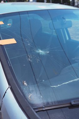 Park halindeki bir arabanın ön camında görünür bir hasar var..