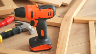 Elektrikli matkap ve el aletleri ahşap çerçevelerin arasında bir tezgahta oturur..