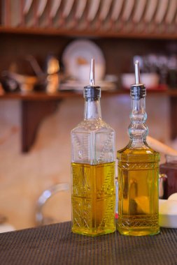 Sıcak bir mutfakta tezgahın üzerinde iki şişe zeytinyağı var..