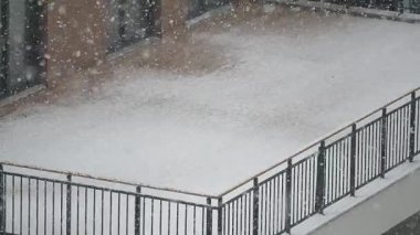 Sakin bir şehir ortamında balkona şiddetli kar yağar..