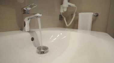 Temiz bir lavabo bölgesindeki musluktan sürekli su akıyor..