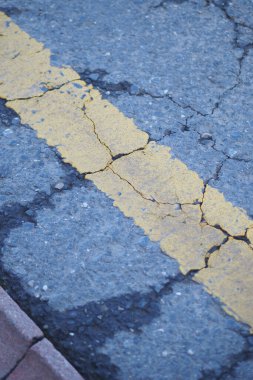 Soluk sarı çizgili çatlak bir yola yakından bak..