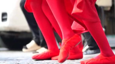 Parlak kırmızı taytlı bir grup dansçı yeteneklerini sokaklarda sergiliyor..