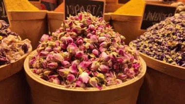 Renkli baharatlar ve kurumuş çiçekler işlek bir pazarda ahşap kapları doldurur..