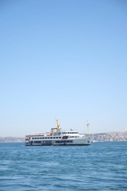 Bir feribot Istanbuls üzerinde süzülüyor. Mavi sular ve kıyı boyunca şehirler..