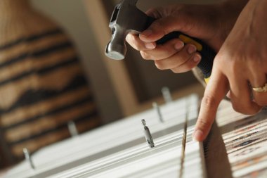 Eller bir proje için tahta bir yüzeye çivi çakıyor..