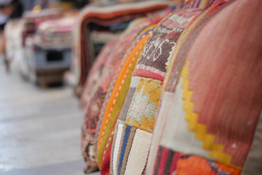 Parlak desenli yastıklar tekstil dolu bir pazar tezgahı hizasında..
