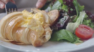 Taze salatayla servis edilen yumurtalarla dolu lezzetli bir kruvasan..