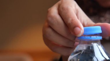 Bir el, su şişesinin kapağını nasıl sorunsuzca ve temiz açacağını gösteriyor..