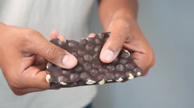 Bir birey elindeki çikolatayı kırar ve dokusunu ortaya çıkarır..