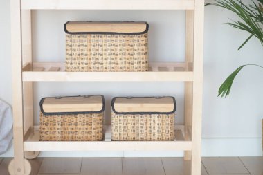 Üç dokuma sepet, açık bir alanda, ahşap bir rafta düzgünce duruyor..