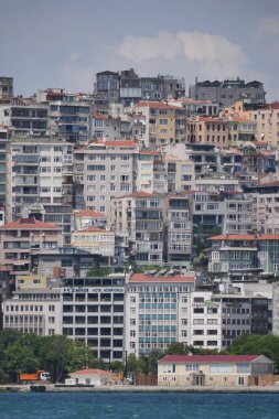 Renkli binalar yamaç boyunca uzanır, mavi gökyüzünün altında sakin bir denize bakar..