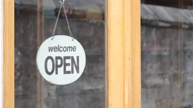 Mağaza vitrininde misafirleri içeri davet eden açık bir tabela asılı..